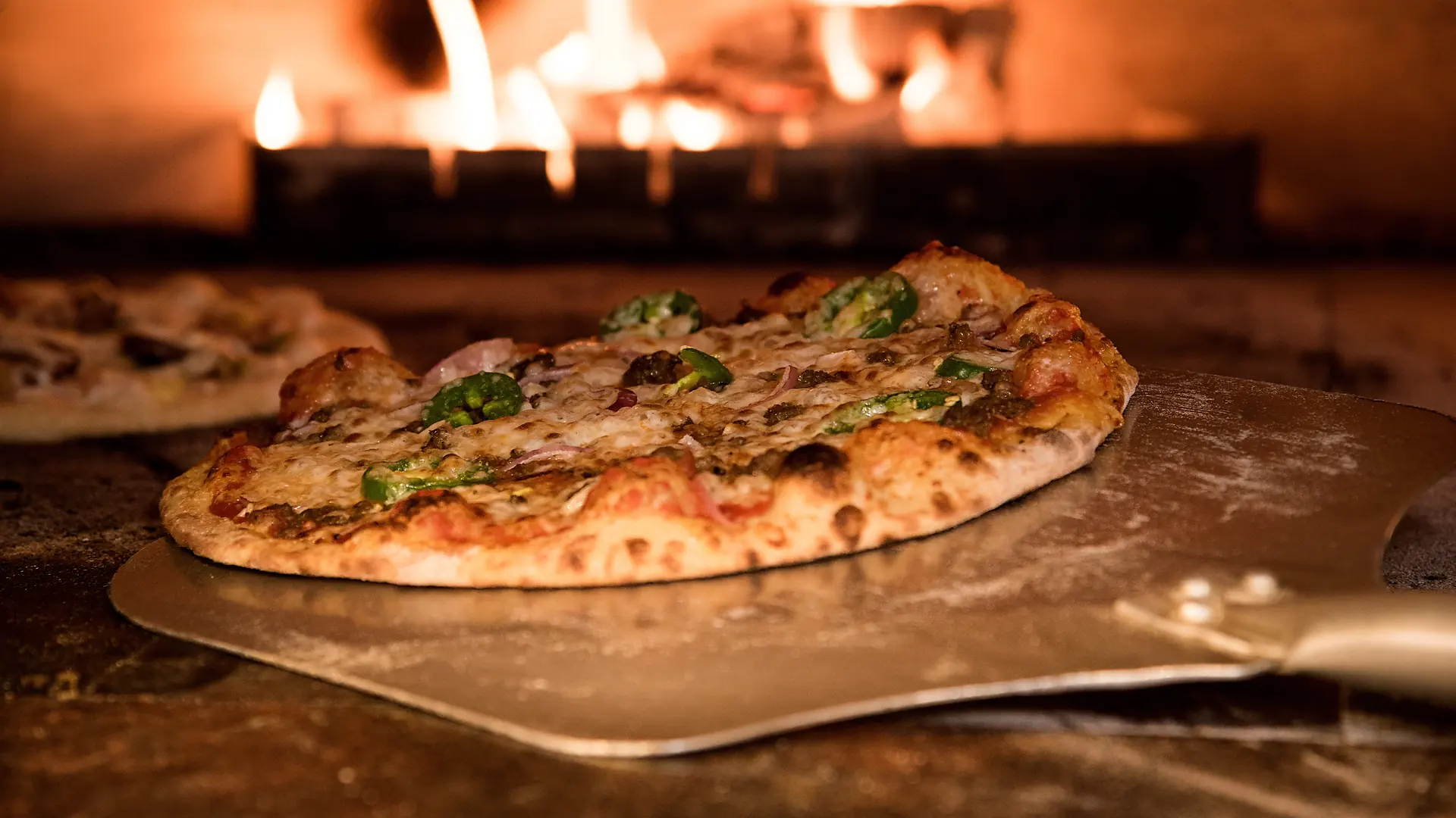 Une pizza sur la pelle, devant le feu de chêne